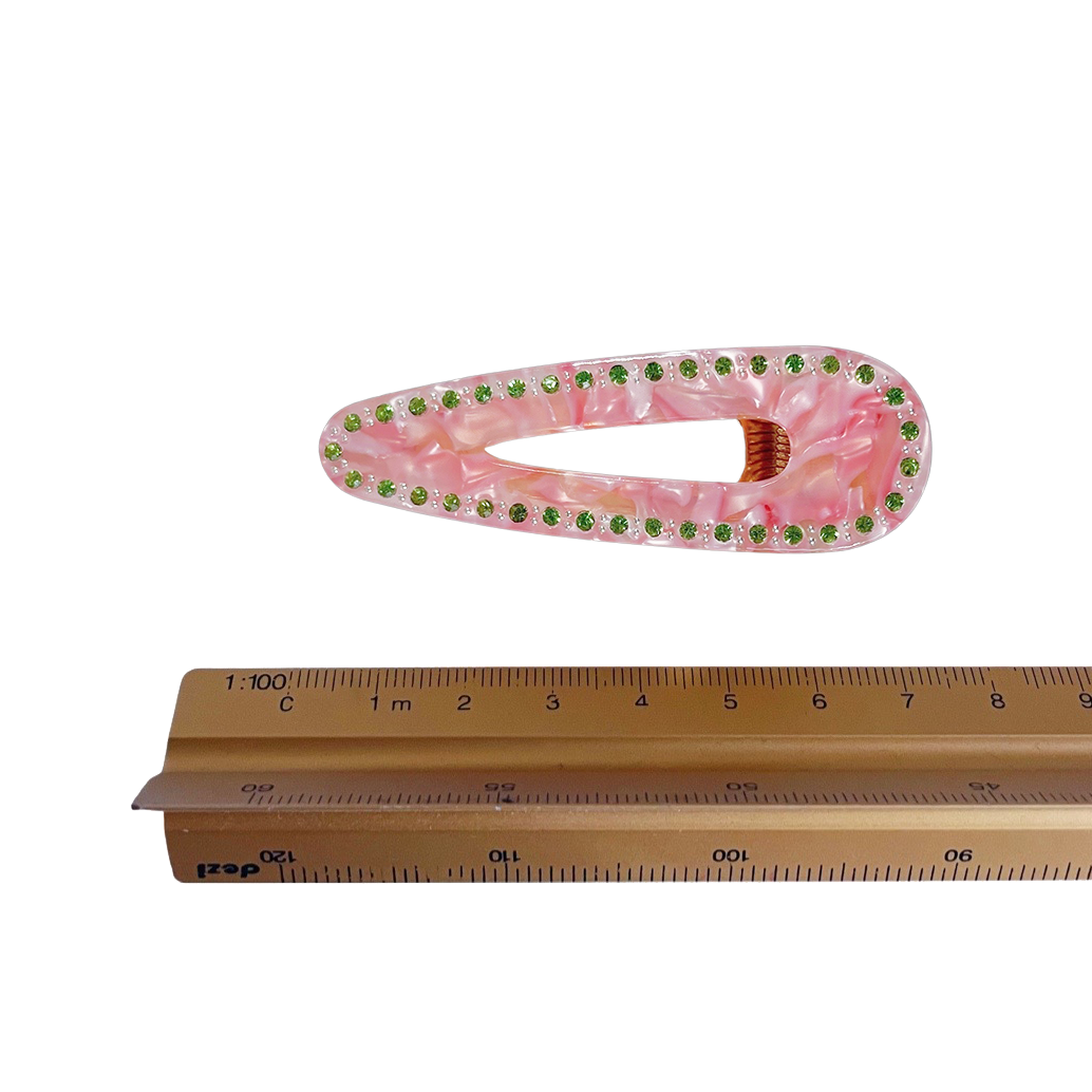 Meet CORA!  Our OG clip, a rounded-edge barrette featuring rhinestones and gold hinge fastening with a teeth effect grip for a sturdy and reliable hold. Great for keeping hair in place or simply clipping back your grown out fringe.  Each clip comes in a branded Tort pouch (colours change seasonally).  Size: 7cm  Colour: peach-pink with lime green rhinestone accents and silver studs  Material: eco-resin 