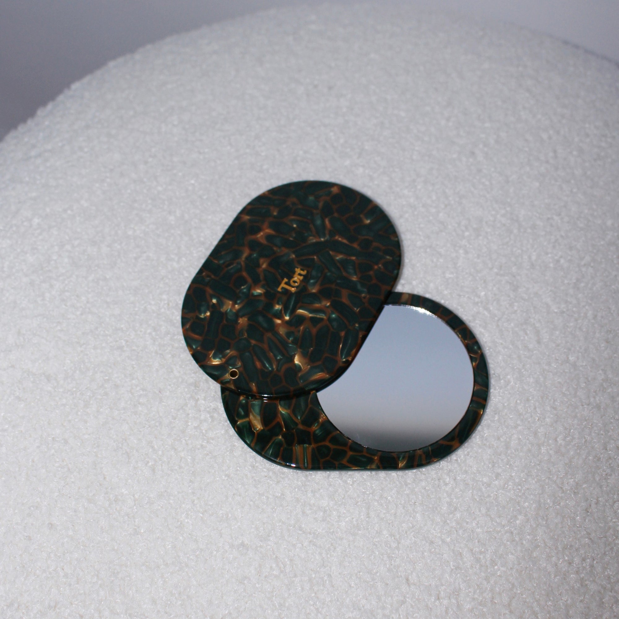Meet JAYA!  A compact mirror is a handbag essential. Made from smooth, hand-poured eco-resin, the JAYA mirror is super cute with added protection and cleanliness through a sliding mechanism.  Each mirror comes in a branded Tort pouch (colours change seasonally).  Size: 10.5cm  Colour: ivy green and bronze mosaic effect  Material: eco-resin