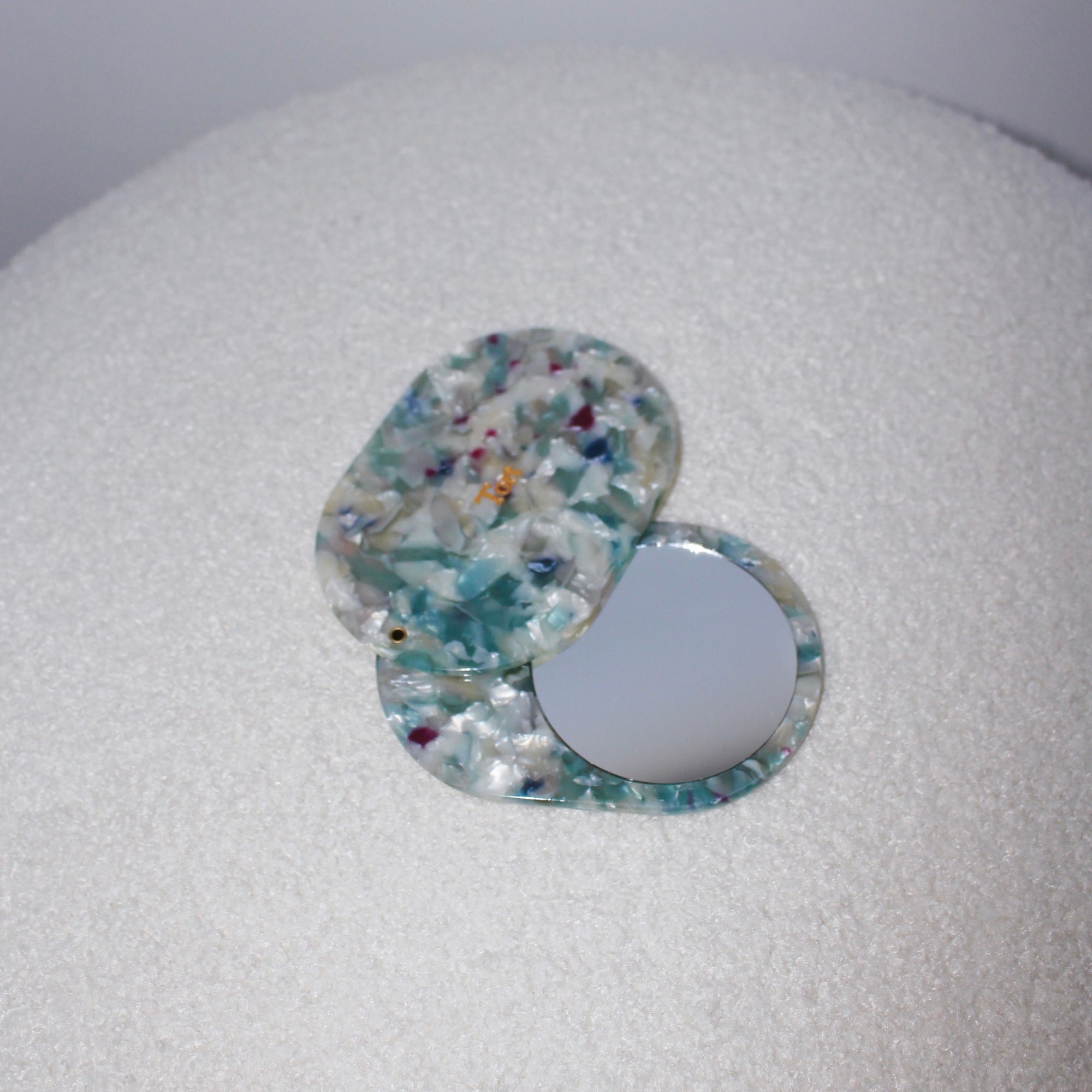 Meet JAYA!  A compact mirror is a handbag essential. Made from smooth, hand-poured eco-resin, the JAYA mirror is super cute with added protection and cleanliness through a sliding mechanism.  Each mirror comes in a branded Tort pouch (colours change seasonally).  Size: 10.5cm  Colour: marbled ice blue, white and green with navy and magenta pieces  Material: eco-resin