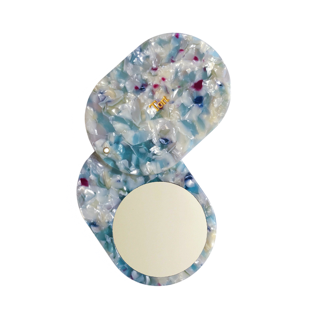 Meet JAYA!  A compact mirror is a handbag essential. Made from smooth, hand-poured eco-resin, the JAYA mirror is super cute with added protection and cleanliness through a sliding mechanism.  Each mirror comes in a branded Tort pouch (colours change seasonally).  Size: 10.5cm  Colour: marbled ice blue, white and green with navy and magenta pieces  Material: eco-resin
