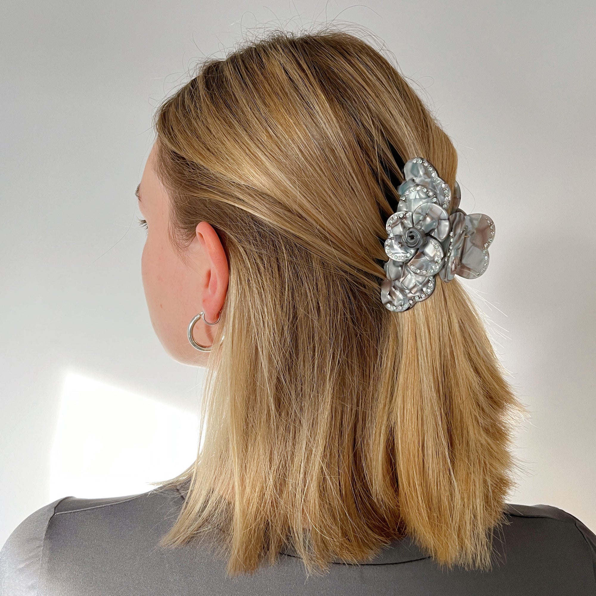 Meet SUZY!  A medium-large clip with flower-shaped detail and rhinestone detailing on each side. Best for half up-half-down looks on thicker hair, while it’s great styled, any-way on medium to fine hair.  Each clip comes in a branded Tort pouch (colours change seasonally).  Size: 9cm  Colour: marbled chocolate brown and warm silver with crystal and green rhinestone accents and silver studs  Material: eco-resin 
