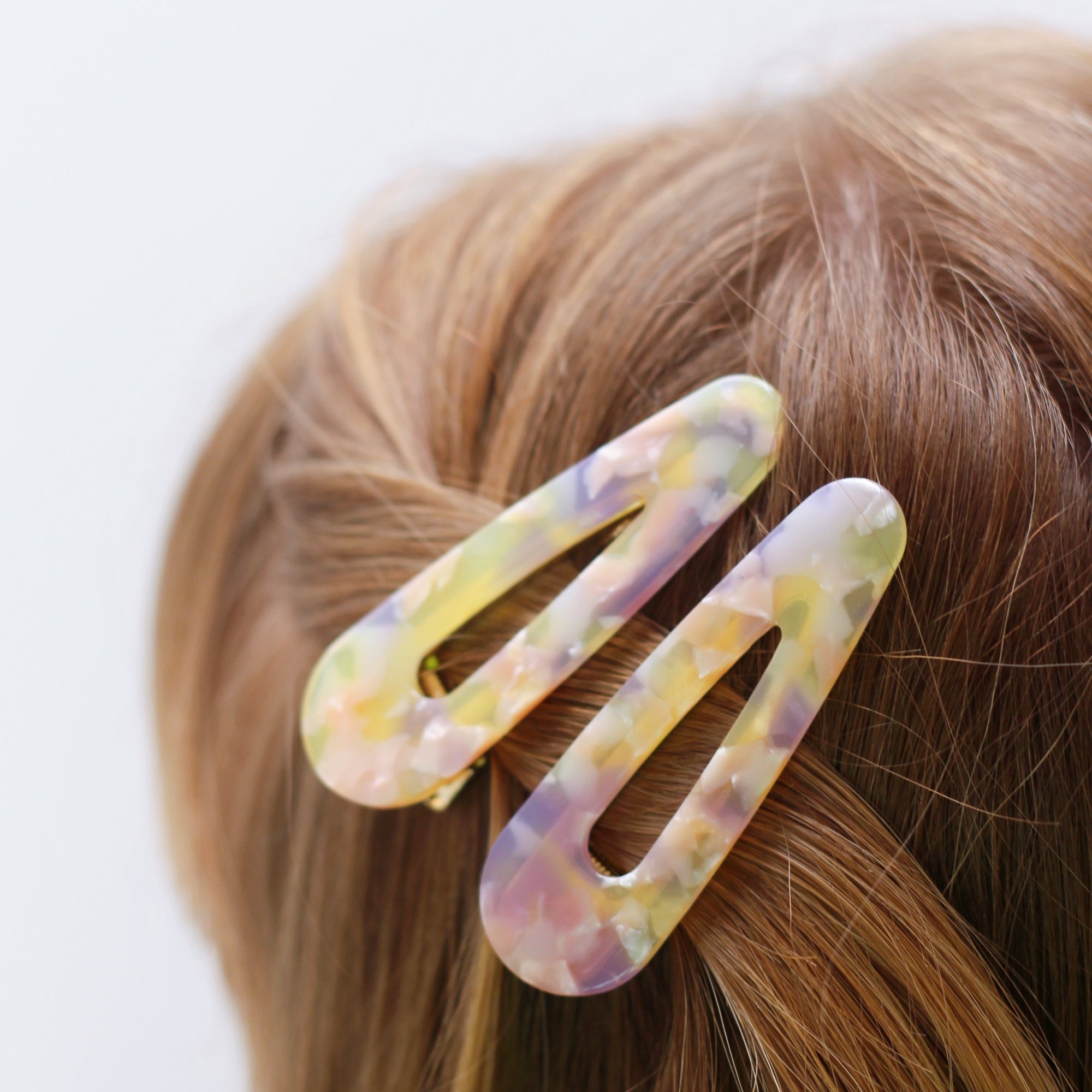 Meet CORA!  Our OG clip, a rounded-edge barrette featuring a gold hinge fastening and a teeth effect grip for a sturdy and reliable hold. Great for keeping hair in place or simply clipping back your grown out fringe.  Each clip comes in a branded Tort pouch (colours change seasonally).  Size: 7cm  Colour: yellow, peach and lilac tie-dye effect  Material: eco-resin