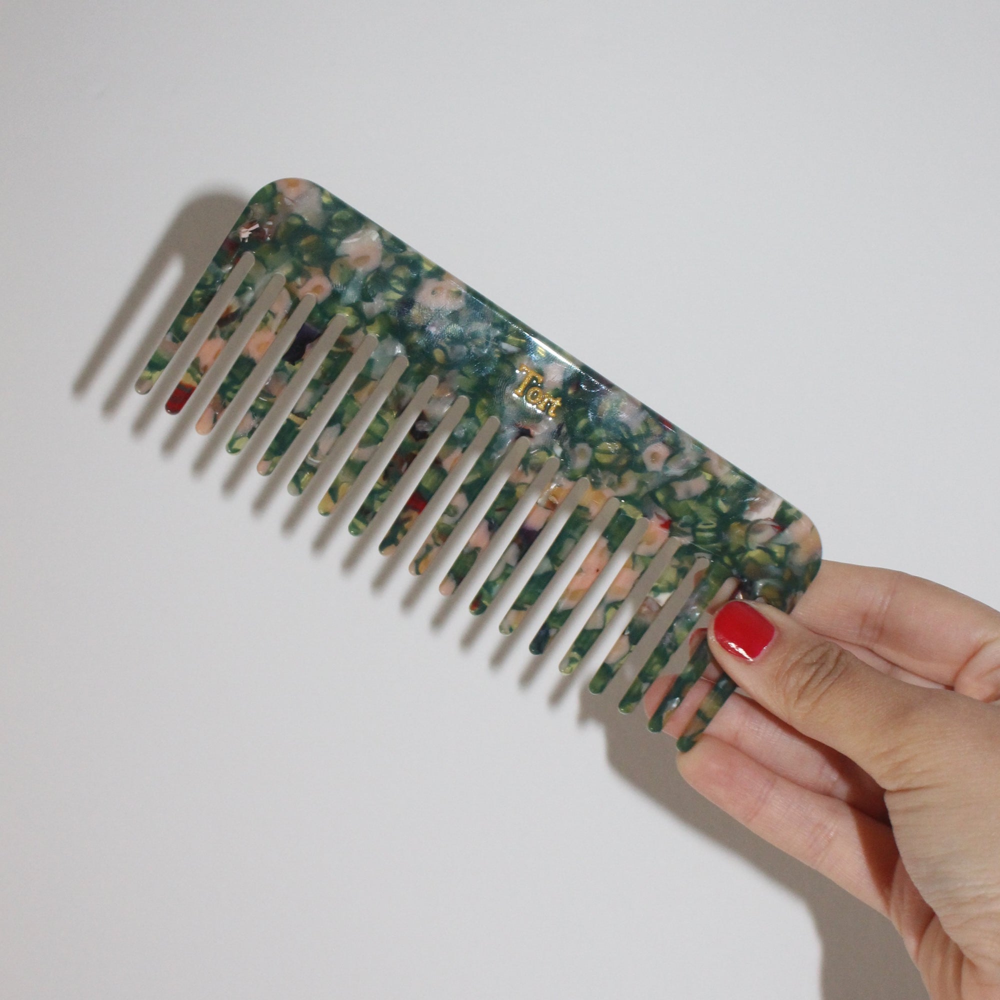 Meet ELVA!  A sturdy round-edged rectangle comb made from eco-resin. Designed with medium positioned rounded teeth so that hair retains texture and strength. Glides through wet or dry hair to untangle or tease after curling with tongs or straighteners, while preventing breakage, split ends and frizz.   Each comb comes in a branded Tort pouch (colours change seasonally).  Size: 15cm  Colour: translucent green and peachy-pink  Material: eco-resin  Combs are non-refundable for hygiene reasons.
