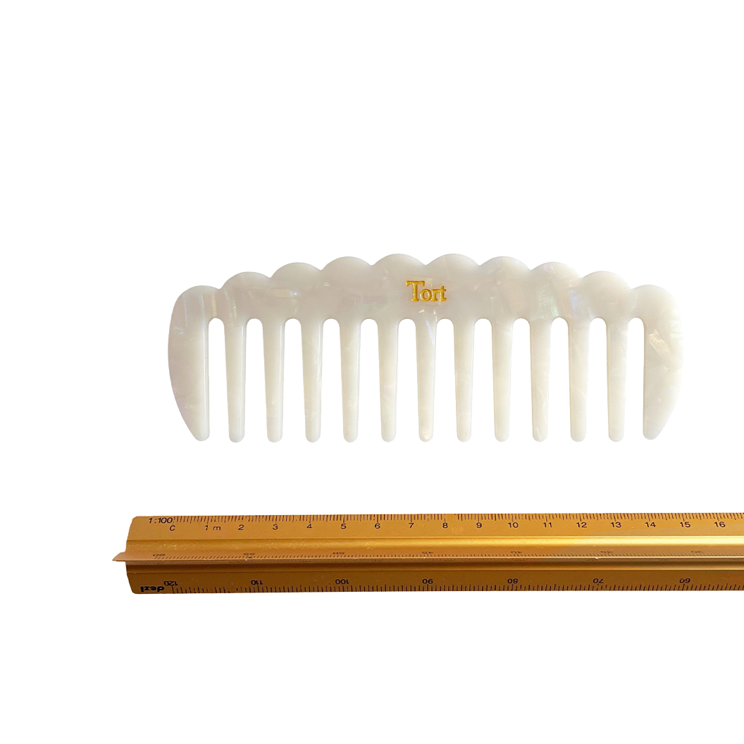 Meet LUCY!  A sturdy scallop edged comb make from eco-resin. Designed with widely positioned rounded teeth so that hair retains texture and strength. Glides through wet or dry hair to gently untangle or tease after curling with tongs or straighteners, while preventing breakage, split ends and frizz. Great for curly hair.  Each comb comes in a branded Tort pouch (colours change seasonally).  Size: 15cm  Colour: marbled pearlescent white  Material: eco-resin  Combs are non-refundable for hygiene reasons.