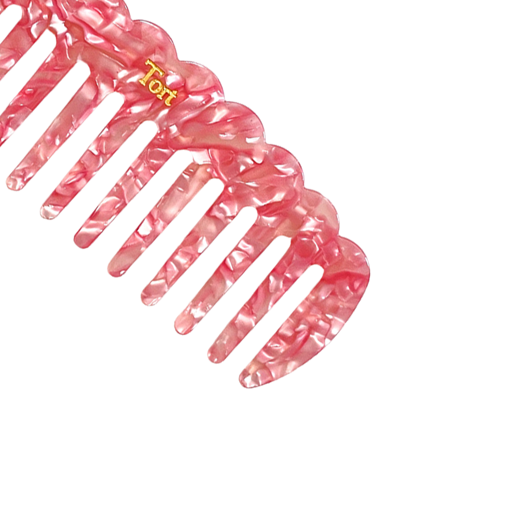 Meet LUCY!  A sturdy scallop edged comb make from eco-resin. Designed with widely positioned rounded teeth so that hair retains texture and strength. Glides through wet or dry hair to gently untangle or tease after curling with tongs or straighteners, while preventing breakage, split ends and frizz. Great for curly hair.  Each comb comes in a branded Tort pouch (colours change seasonally).  Size: 15cm  Colour: pearlised light pink  Material: eco-resin  Combs are non-refundable for hygiene reasons. 