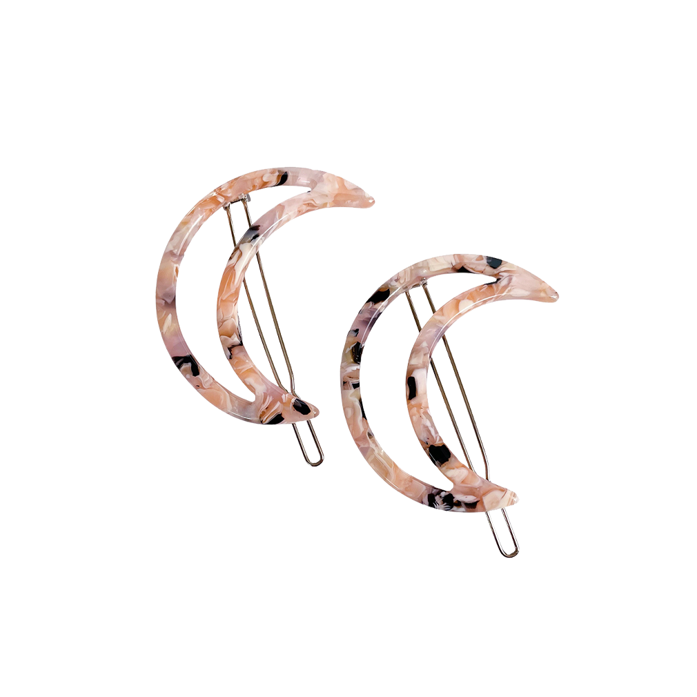 Meet LUNA!  A pair of moon shaped clips with a pin clasp. Either use to clip a section of hair back or to clip around a low bun or ponytail.  Each clip comes in a branded Tort pouch (colours change seasonally).  Size: 6cm  Colour: marbled peach and lilac  Material: eco-resin
